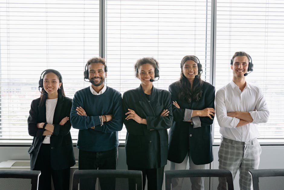 Diverse group of smiling customer service agents wearing headsets in modern office.